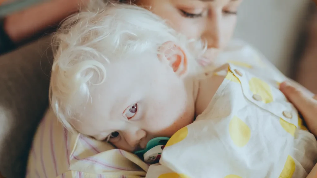 Küçük çocuk bakıcının omzuna uzanmış